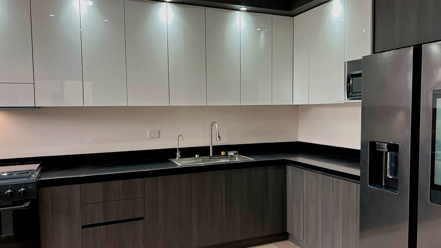 Cocina integral en L con alacenas blanco alto brillo y gabinetes en grafito maderado