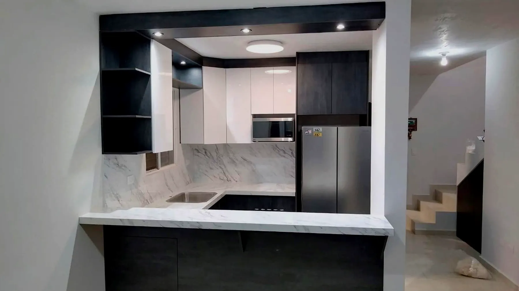 Cocina en U con barra y salpicadero efecto mármol y gabinetes en grafito